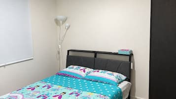 A bedroom with a bed, a bedside table, a lamp, and a wardrobe.