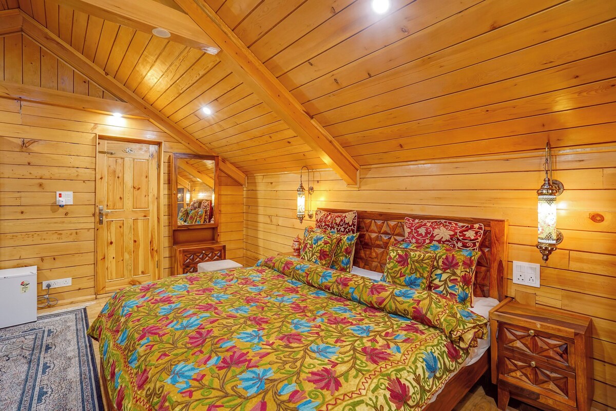 A wooden cabin bedroom with a bed, nightstands, and a dresser.