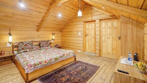 Interior de madeira com cama, mesa de cabeceira, tapete e porta.