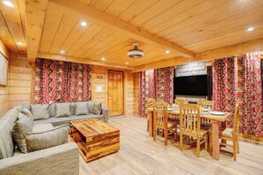A wooden interior with a sofa, dining table, chairs, and a TV. - DanCenter Riverside Lexus Regency (Pahalgam)