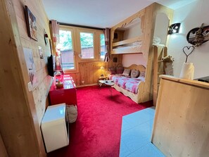 A cozy room with a bunk bed, a small table, and a red carpet. - Cozy apartment, pets welcome - 4 guests (Avoriaz)