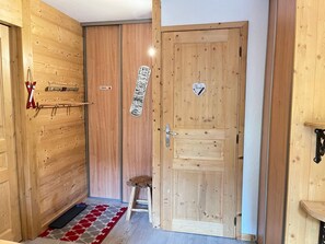 A wooden door with a heart-shaped decoration, a small stool, and a red and white patterned rug. - Cozy apartment, pets welcome - 4 guests (Avoriaz)