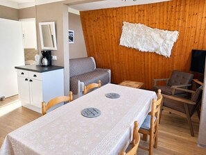 A compact living space with a kitchenette, a dining table, a sofa, and a TV. - Cozy apartment, pets welcome - 6 guests (Saint-Michel-de-Chaillol)