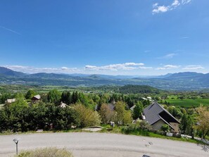 Ein Wohngebiet mit Häusern, umgeben von Grünflächen und Bergen im Hintergrund.