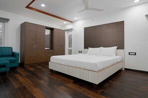 Une chambre à coucher moderne avec un grand lit, une armoire et un ventilateur de plafond.