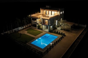 Una casa moderna de dos pisos con piscina y césped bien cuidado.