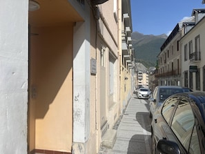 A narrow street with buildings on both sides, a parked car, and a mountain in the background. - Central studio for 4 guests - Cauterets centre (Cauterets)