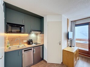 A compact kitchen with a microwave, toaster, and dishwasher. - Les Menuires - Cozy studio for 4 guests (Les Menuires)