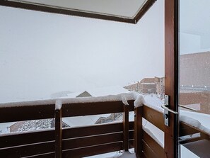 A balcony with a wooden railing and a glass door leading to a snowy outdoor area. - Les Menuires - Cozy studio for 4 guests (Les Menuires)