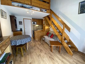 A cozy cabin interior with a dining area, kitchenette, and a wooden staircase. - Mezzanine studio near slopes - 4 guests (Arêches-Beaufort)