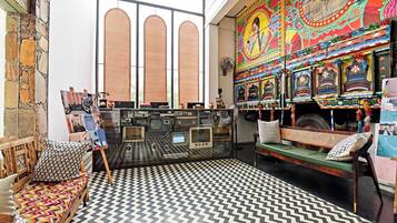 Una habitación con un ventanal grande, un mural colorido, una radio antigua y un suelo con diseño.