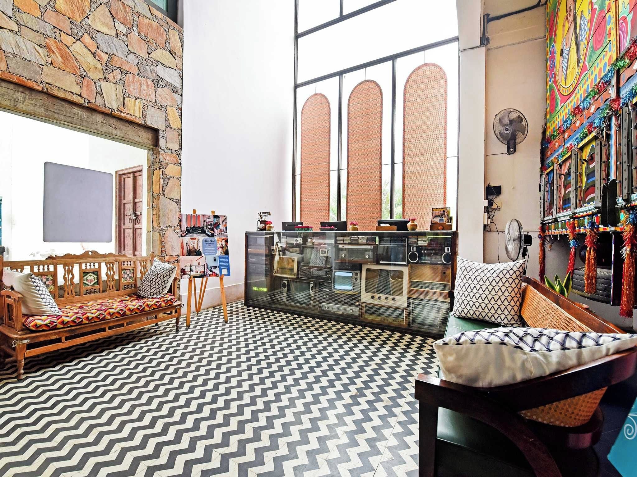 Una habitación con pared de piedra, un banco de madera, suelo estampado y una decoración de pared colorida.