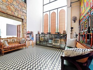 Una habitación con pared de piedra, un banco de madera, suelo estampado y una decoración de pared colorida.