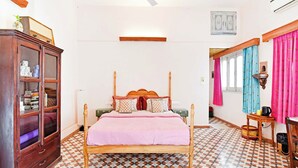 Un dormitorio con una cama, un armario de madera, un ventilador de techo y baldosas de suelo con diseño.