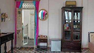 Una habitación con piso estampado, un mueble de madera, un electrodoméstico blanco pequeño y una puerta que da a otra habitación.