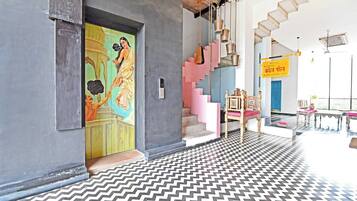 A modern interior with a chevron-patterned floor, a staircase with pink steps, and a traditional Indian painting on the wall.