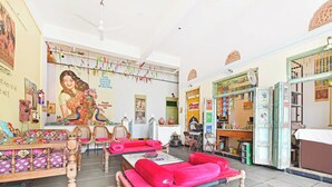 Una habitación con una cama, una mesa con sillas, un mural en la pared y una puerta con un letrero.