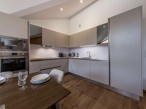 A modern kitchen with built-in appliances, a dining table with chairs, and a wooden floor. - Spacious apartment panoramic view - 8 guests (Courchevel 1650)