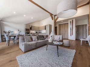 A modern living room with a sofa, coffee table, and dining area. - Spacious apartment panoramic view - 8 guests (Courchevel 1650)