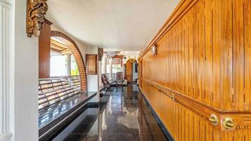 A hallway with a wooden wall, a bench, and a tiled floor.
