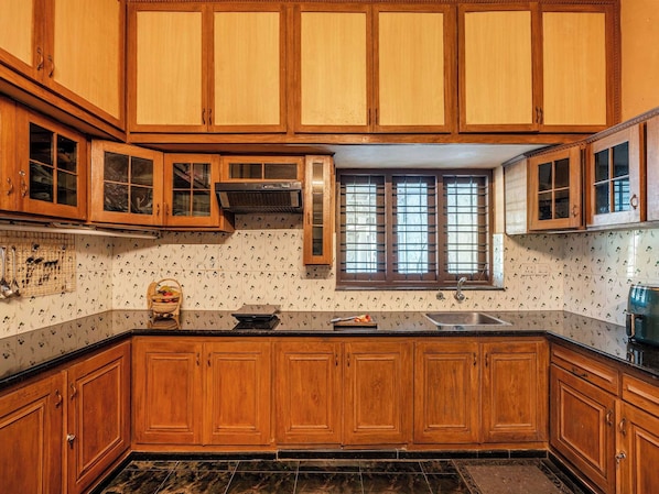 A kitchen with wooden cabinets, a window with blinds, and a tiled backsplash.