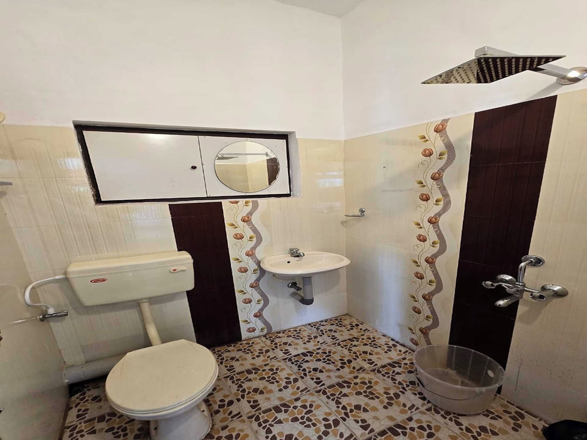 Un baño con inodoro, lavamanos y un espejo sobre el lavamanos.