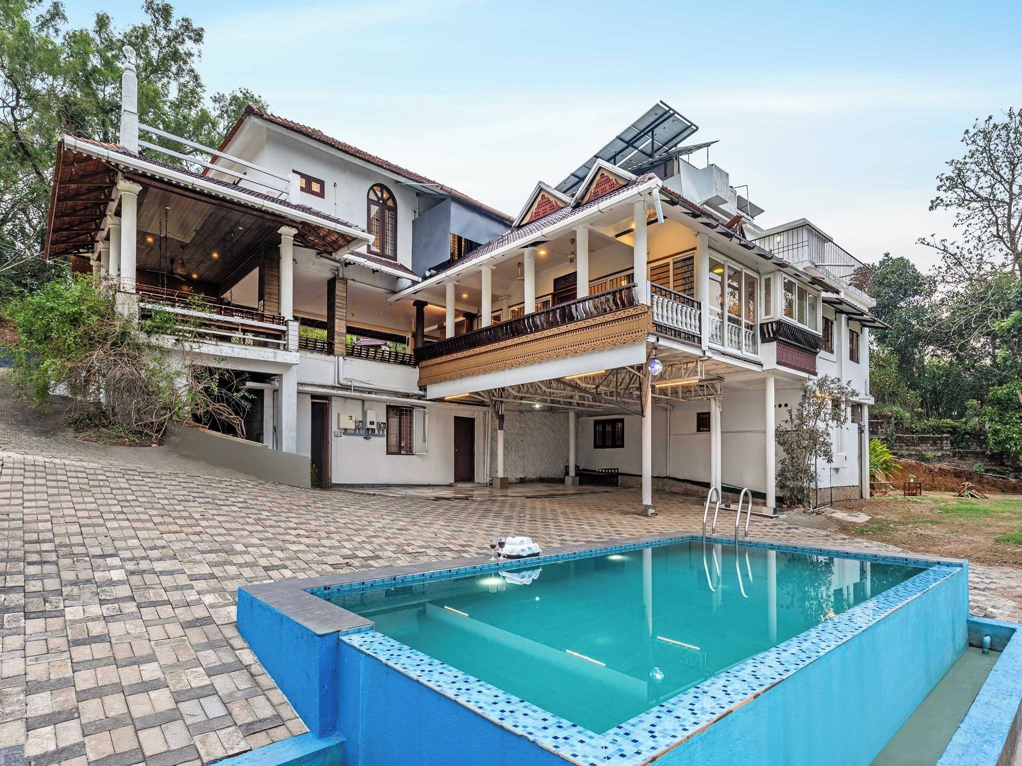 Una casa de dos pisos con piscina, ventanas amplias y un balcón.