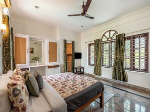 Un dormitorio con cama, armario, televisor y ventana con cortinas.