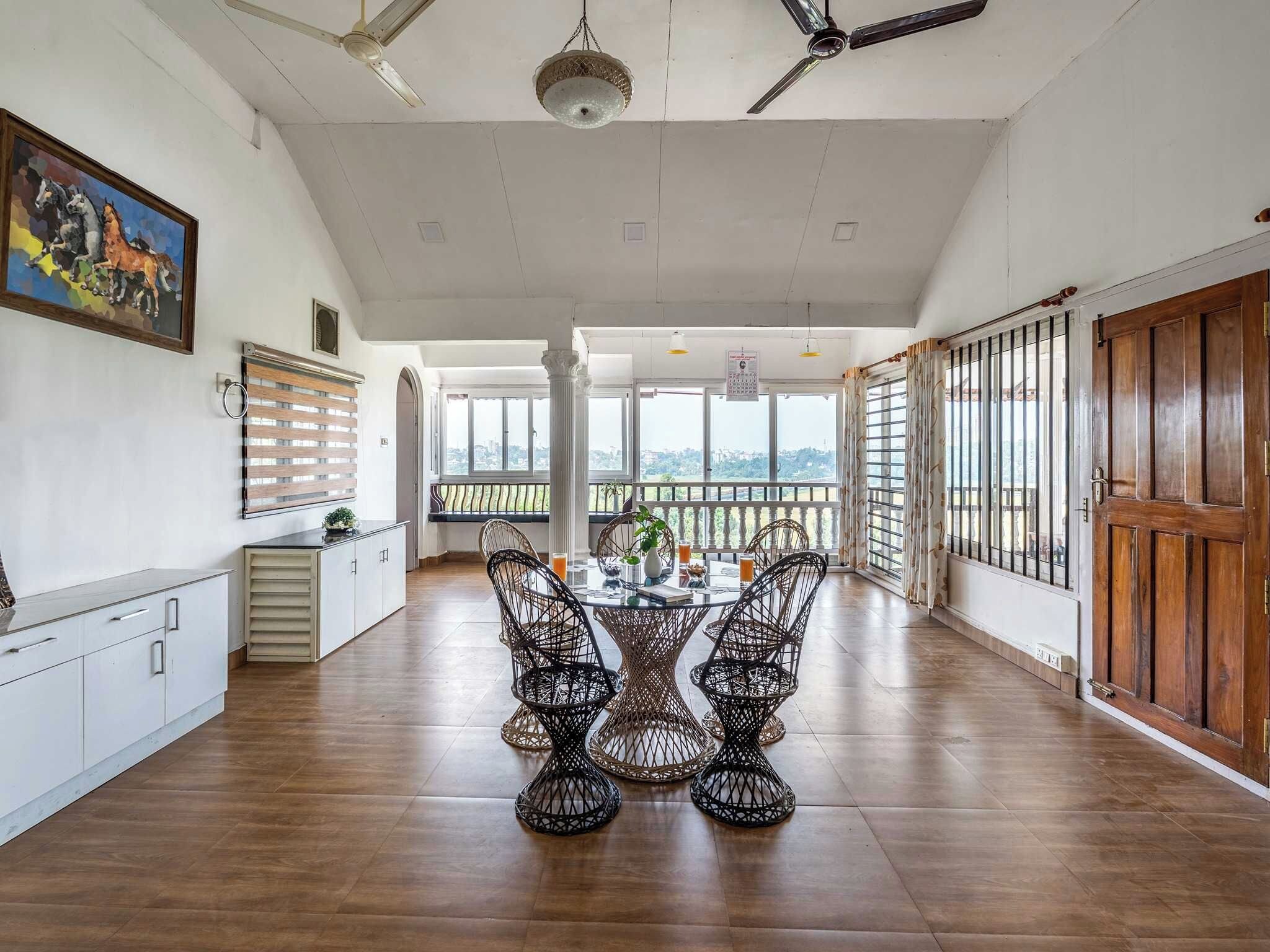 A spacious dining area with a high ceiling, large windows, and a view of the cityscape.