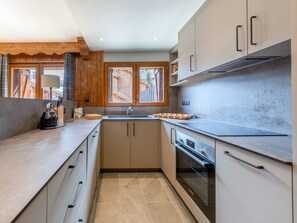 A modern kitchen with a built-in oven, a sink, and wooden cabinets. - Charming apartment - 7 guests, south terrace (Val-d'Isère)