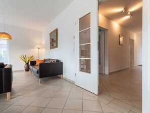 A modern living room with a sofa, a lamp, and a vase of flowers. - Holiday Home With 3 Bedrooms (St. Peter-Ording)