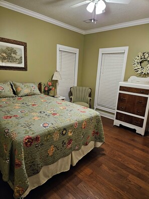 Une chambre à coucher avec un lit, une chaise, une commode et une fenêtre avec des stores.
