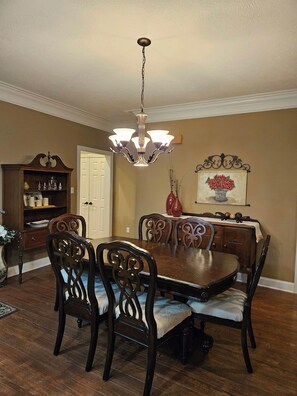 A dining room with a wooden table and chairs, a chandelier, a bookshelf, and a door. - Tranquil Lakeside Retreat II (Milan)