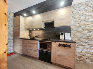 A modern kitchen with wooden cabinets, a built-in oven, and a stone backsplash. - Ideal T2 apartment for 4 guests - Samoëns (Samoëns)