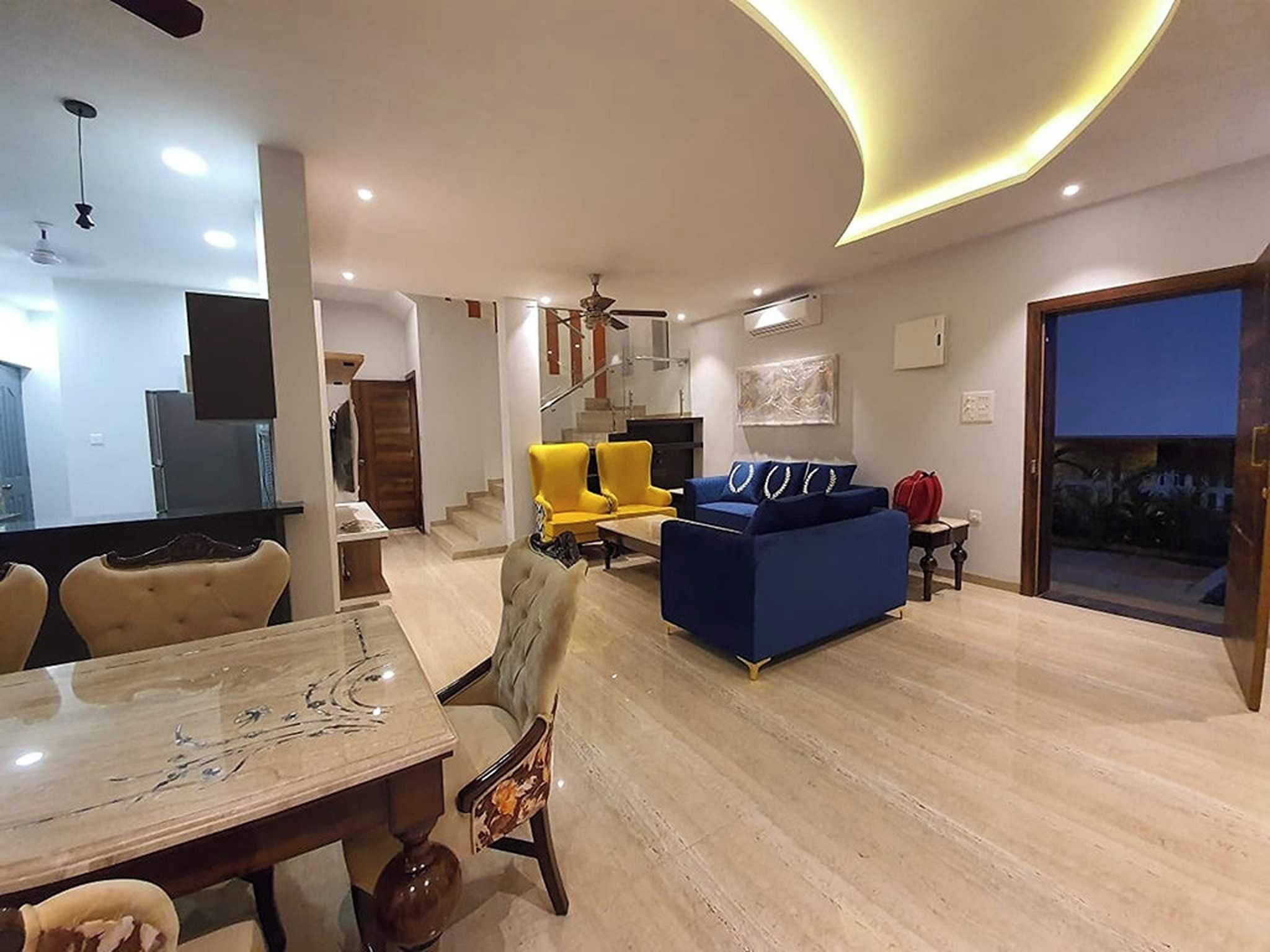 Een moderne woonkamer met een eethoek, een trap en een groot raam.