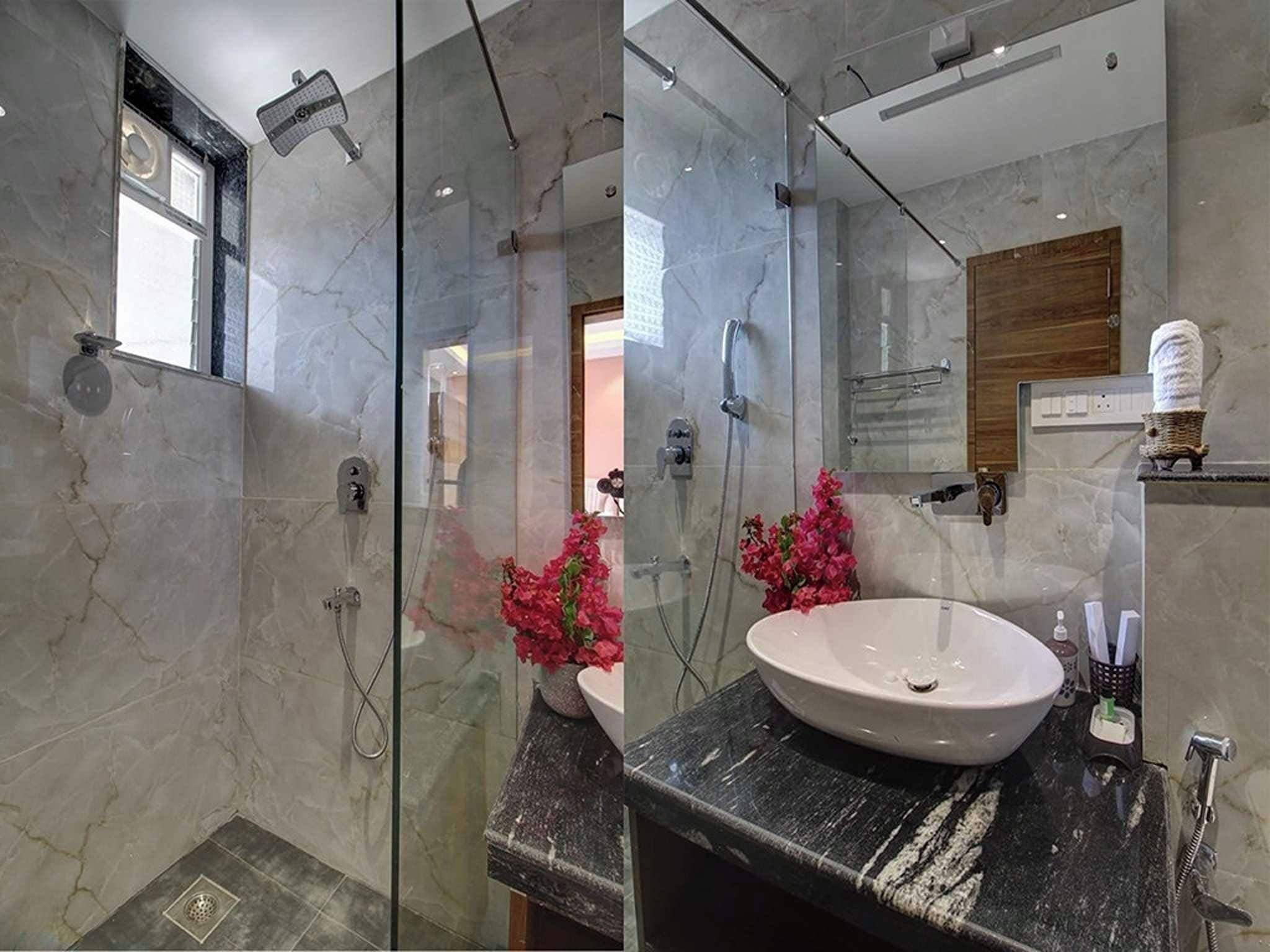 Een moderne badkamer met een douchecabine van glas, een marmeren wastafel en een zichtbaar toilet.