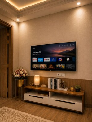 A modern living room with a flat-screen TV mounted on the wall displaying a streaming service interface.