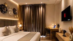 Ein modernes Hotelzimmer mit einem großen Bett, einem Schreibtisch, einem Fernseher und einem Deckenventilator.