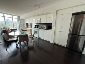 A modern kitchen with a dining area, large windows, and a view of the city.