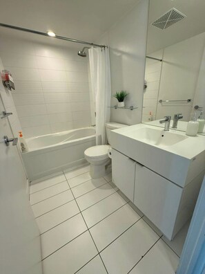A modern bathroom with a bathtub, toilet, and vanity with a mirror.