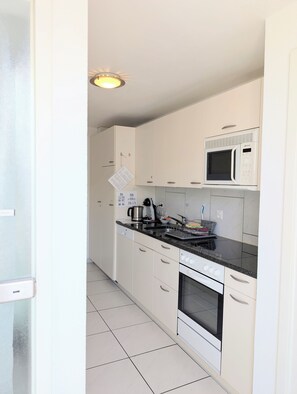 A modern kitchen with white cabinets, a black countertop, a built-in oven, and a microwave. - The Centralstrasse Apartment | Heart of Interlaken (Interlaken)