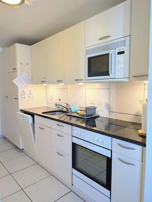 A modern kitchen with white cabinetry, a built-in microwave, a dishwasher, and an oven. - The Centralstrasse Apartment | Heart of Interlaken (Interlaken)