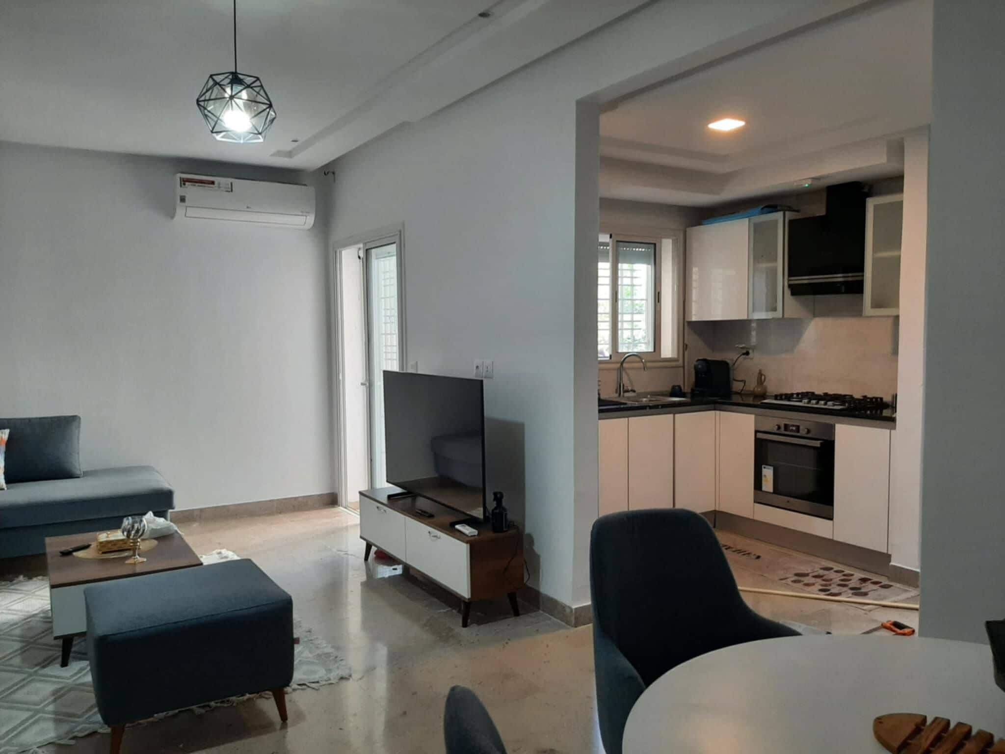 Una sala moderna con un sofá, una otomana y un televisor de pantalla plana.