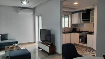 Una sala moderna con un sofá, una otomana y un televisor de pantalla plana.