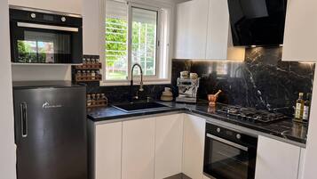 Una cocina moderna con horno empotrado, refrigerador de acero inoxidable y encimera negra.