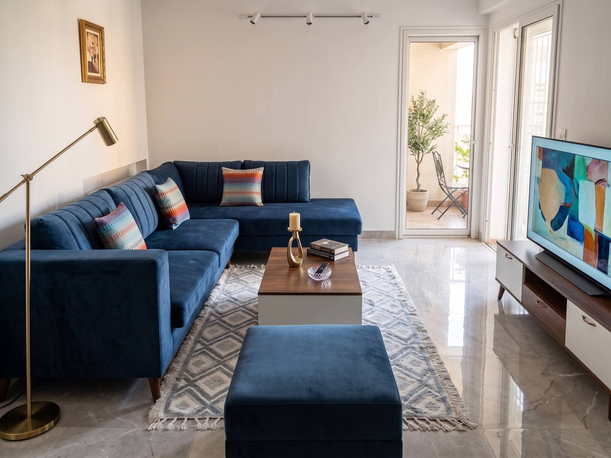 Una sala de estar moderna con un sofá seccional azul, una mesa de centro, una lámpara de pie y un televisor.