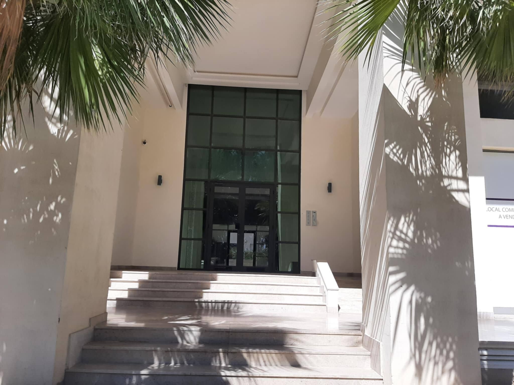 A building entrance with a set of stairs leading up to a glass door.