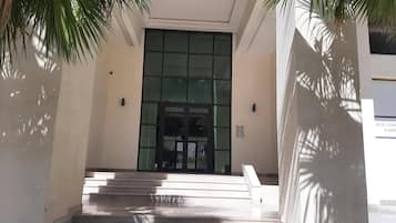 A building entrance with a set of stairs leading up to a glass door.