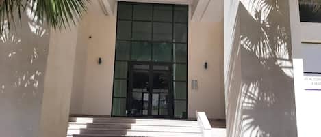 A building entrance with a set of stairs leading up to a glass door.