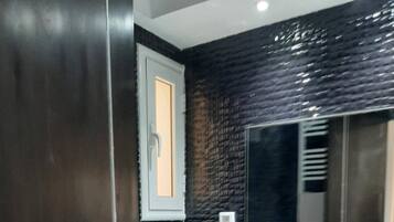 A modern bathroom with a black tiled wall, a white sink, and a mirror.